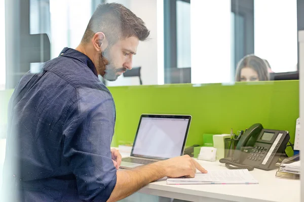 Zakenman met laptop lezen boek bij Bureau — Stockfoto