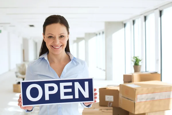 Smiling businesswoman holding open sign — Stock Photo, Image