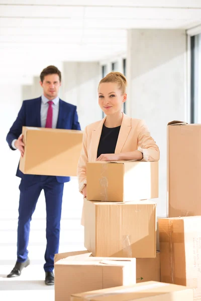 Businesswoman standing by stacked boxes with colleague — Stock Photo, Image