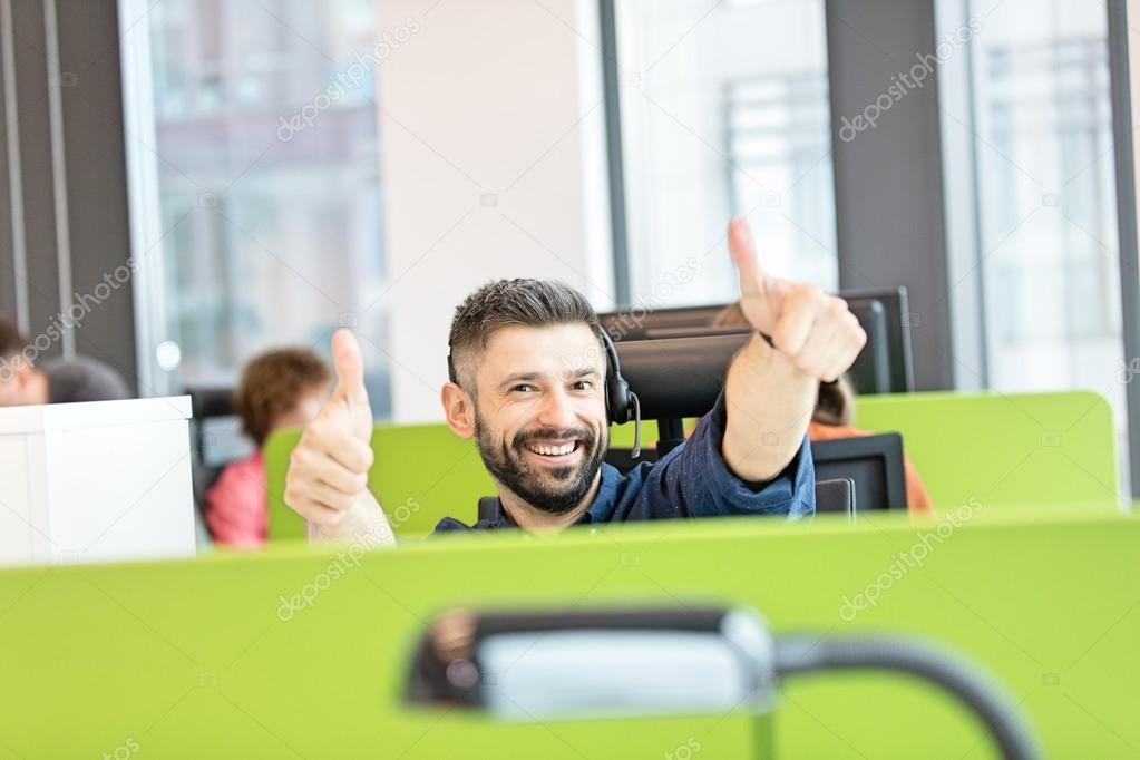 happy businessman gesturing thumbs up in office 