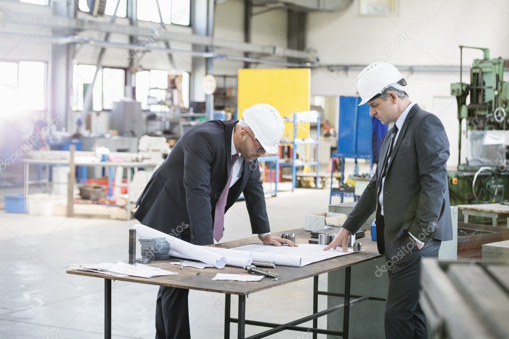 Businessmen examining blueprint at workbench 