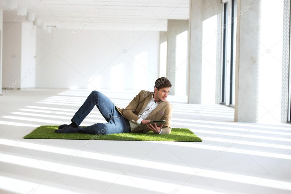 businessman reclining on turf with digital tablet   