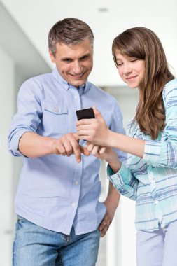 Father and daughter using smartphone clipart