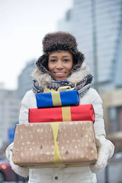 Woman carrying stacked gifts — Stock Photo, Image