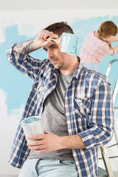 Tired man holding paint can — Stock Photo, Image