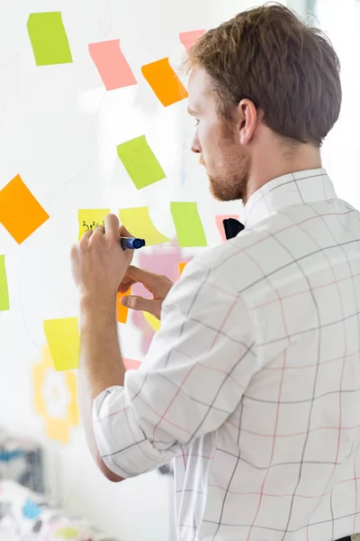 Businessman writing on sticky paper — Stock Photo, Image