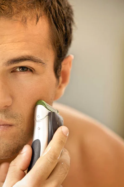 Чоловік голиться з електричною бритвою — стокове фото