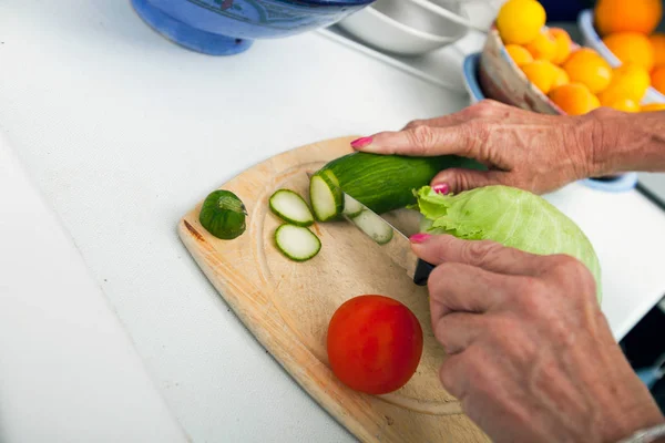 Senior vrouw snijden groenten — Stockfoto