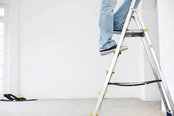 Man in spijkerbroek op ladder — Stockfoto