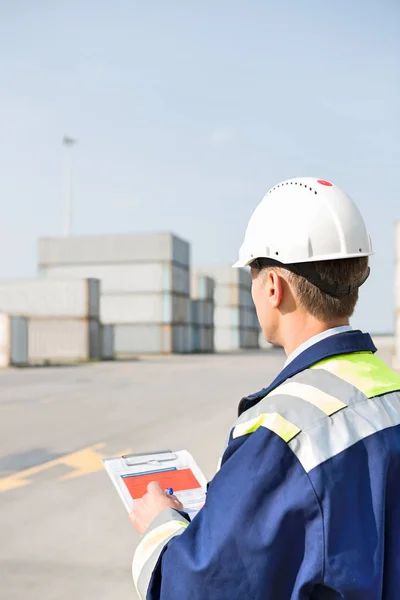 Worker with clipboard in shipping yard — Stock Photo, Image