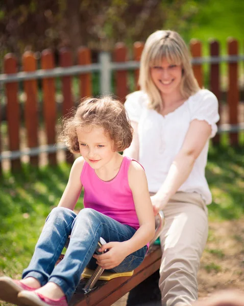 Mother and daughter ride seesaw — Stock Photo, Image