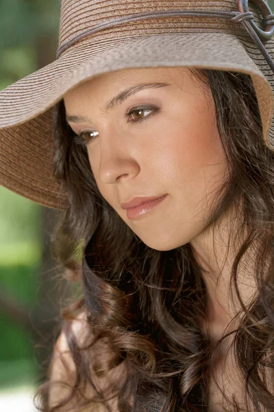 Woman wearing sun hat in park — Stok fotoğraf