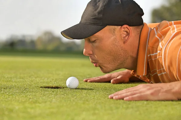 Homme soufflant sur la balle de golf — Photo