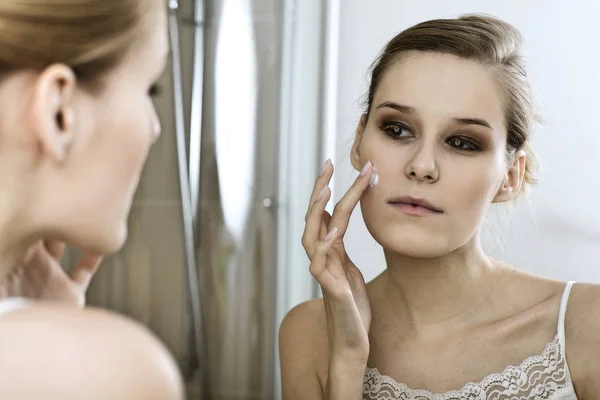 Mujer joven aplicando crema de belleza —  Fotos de Stock