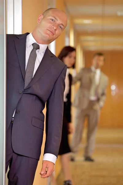 Businessman standing at door while colleagues — Stock Photo, Image