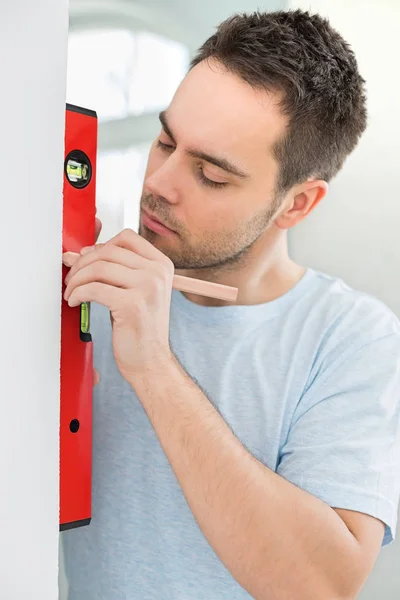 Mann markiert Wand mit Ebene — Stockfoto