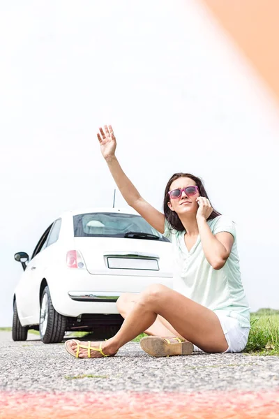 Woman hitchhiking while using cell phone — Stock Photo, Image