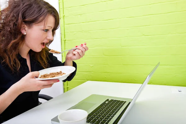 Kvinna som äter på skrivbord — Stockfoto