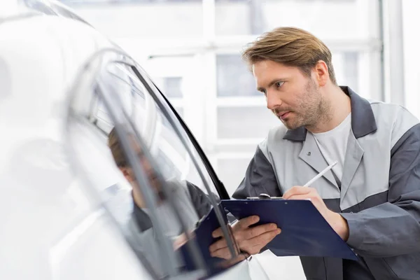 Reparera arbetare samtidigt undersöka bil — Stockfoto