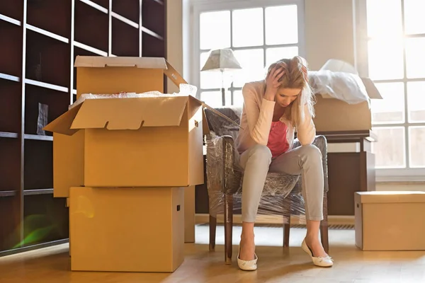 Frustrated woman sitting by cardboard boxes — Stock Photo, Image