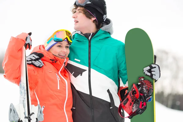 Casal com snowboard e esquis — Fotografia de Stock