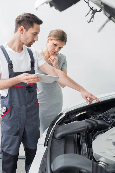 Trabajador de reparación que explica el motor del coche — Foto de Stock