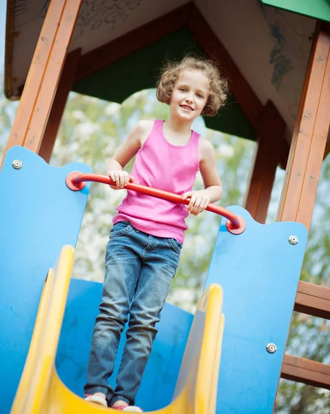 Girl standing at top of slide — Stock Photo, Image