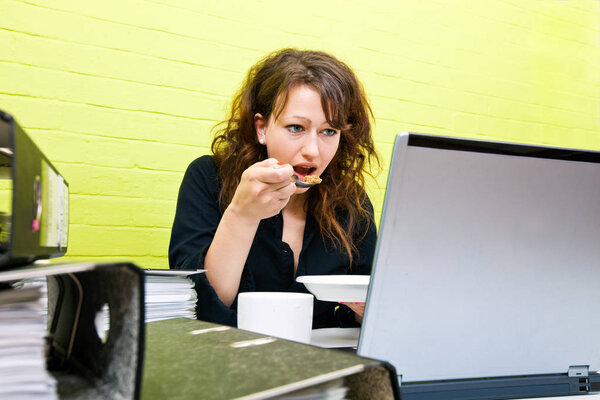 Young woman eating and working