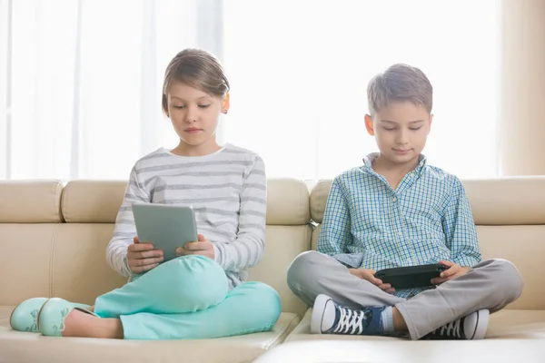 Cute siblings using devices — Stock Photo, Image