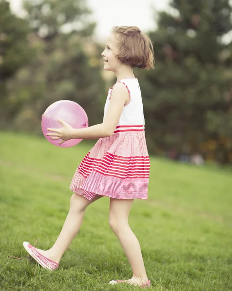Девушка играет с фиолетовым мячом — стоковое фото