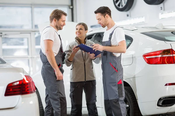 Automobile mechanics discussing over clipboard — Stock Photo, Image