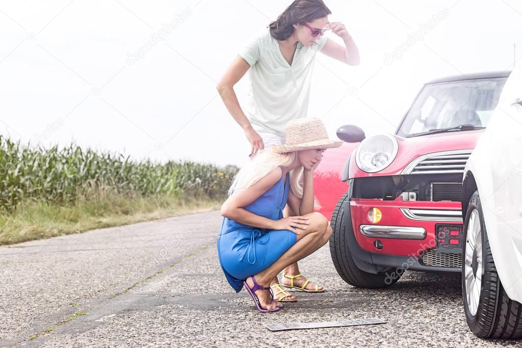 Tensed women looking at damaged cars 