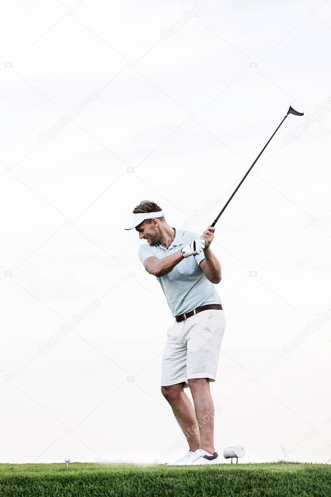 mid-adult man swinging golf club 