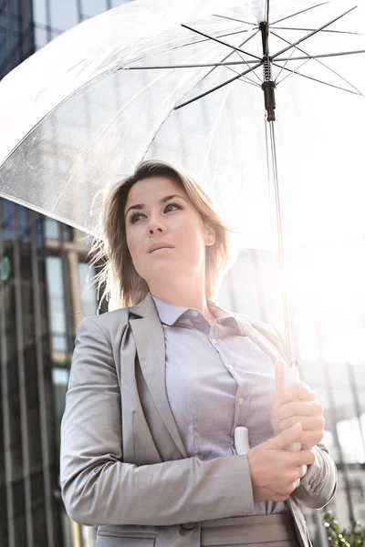 Nachdenkliche Geschäftsfrau mit Regenschirm — Stockfoto