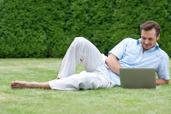 Man använder laptop liggande på gräs — Stockfoto