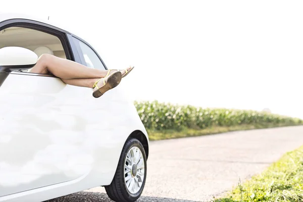 Woman relaxing in car on country road — Stock Photo, Image