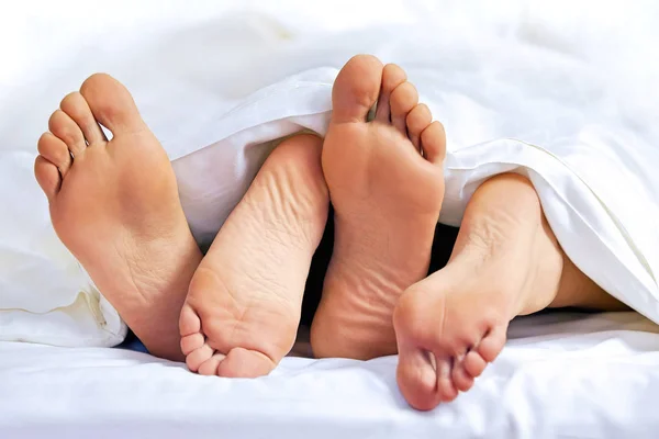 Fötter i ett par på sängen — Stockfoto