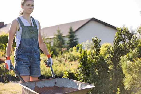 Vrouwelijke tuinman duwen kruiwagen — Stockfoto