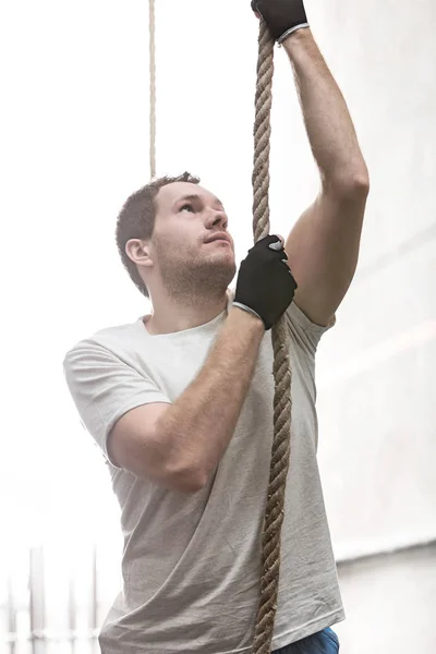 Determined man climbing rope — Stock Photo, Image