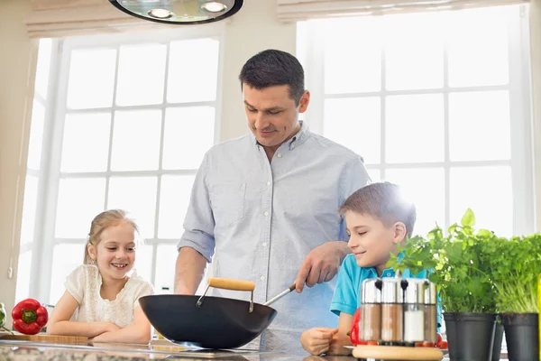 Kinder betrachten Vater bei der Essenszubereitung — Stockfoto