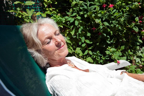 Äldre kvinna avkopplande på solstol — Stockfoto