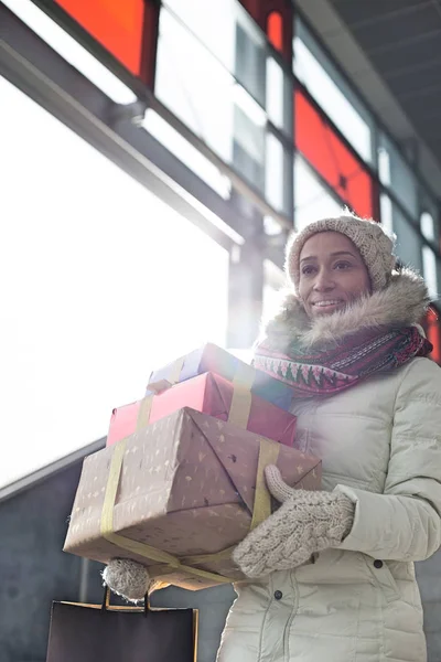 Mujer sonriente llevando regalos apilados — Foto de Stock