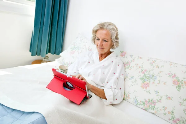 Ηλικιωμένη γυναίκα που χρησιμοποιεί ψηφιακό δισκίο — Φωτογραφία Αρχείου