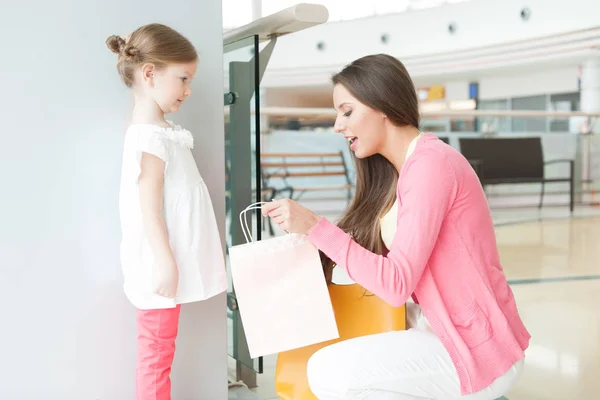 Mother giving daughter shopping bag — Stock Photo, Image