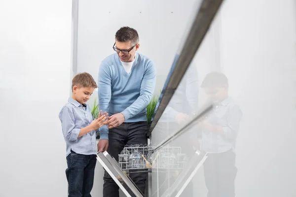 Vater und Sohn stellen Glas in Spülmaschine — Stockfoto