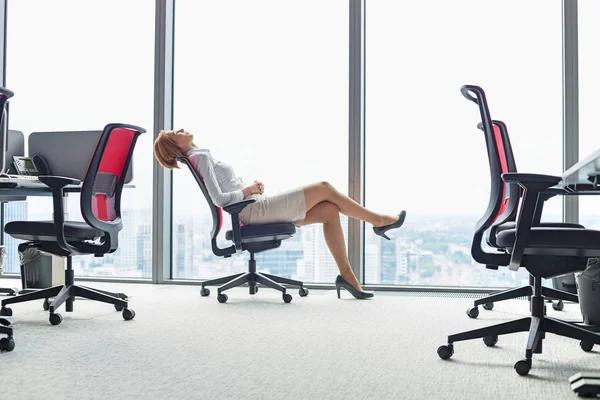 Geschäftsfrau lehnt sich im Büro im Stuhl zurück — Stockfoto