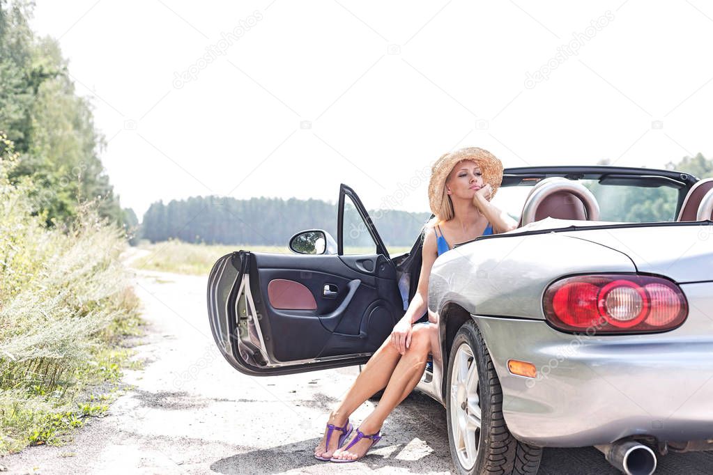 Thoughtful woman sitting in convertible