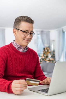 Kredi kartı ve laptop kullanan bir adam. 
