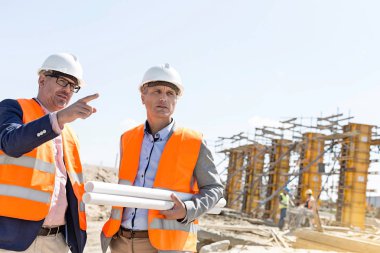 Male engineers discussing at construction site clipart