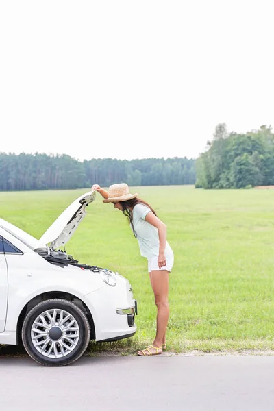 Mujer examinando coche averiado — Foto de Stock